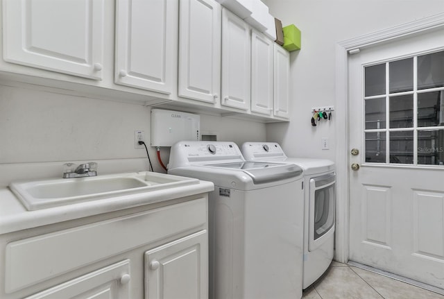 clothes washing area with sink, light tile patterned floors, cabinets, and independent washer and dryer