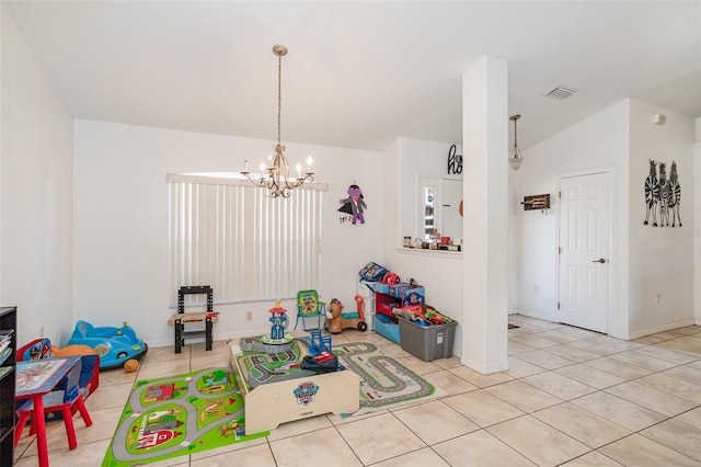 playroom featuring lofted ceiling, light tile patterned floors, and an inviting chandelier