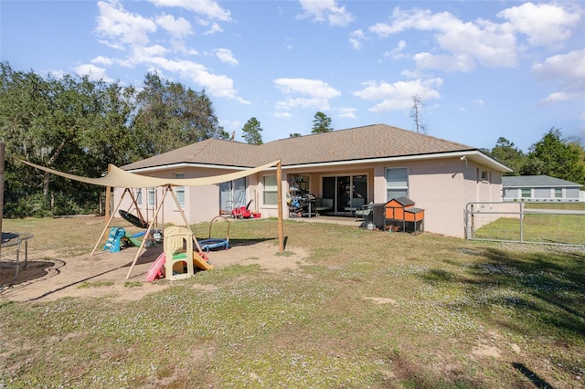 rear view of house featuring a trampoline, a patio area, and a lawn