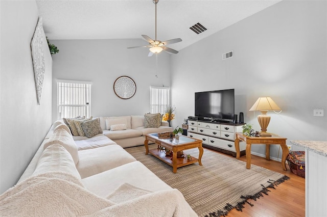 living room featuring ceiling fan, plenty of natural light, high vaulted ceiling, and light hardwood / wood-style floors