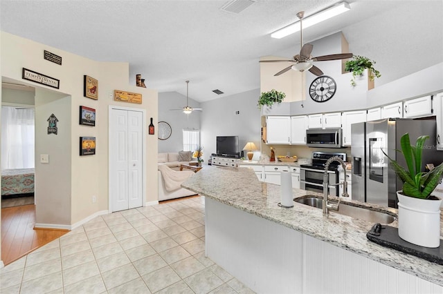 kitchen featuring white cabinets, sink, vaulted ceiling, light wood-type flooring, and appliances with stainless steel finishes