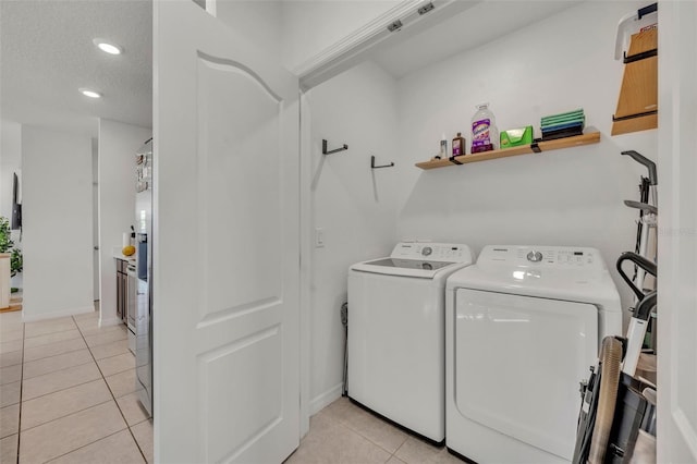 laundry area featuring light tile patterned floors, a textured ceiling, and washing machine and clothes dryer