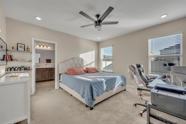 carpeted bedroom featuring multiple windows, ceiling fan, ensuite bath, and a textured ceiling