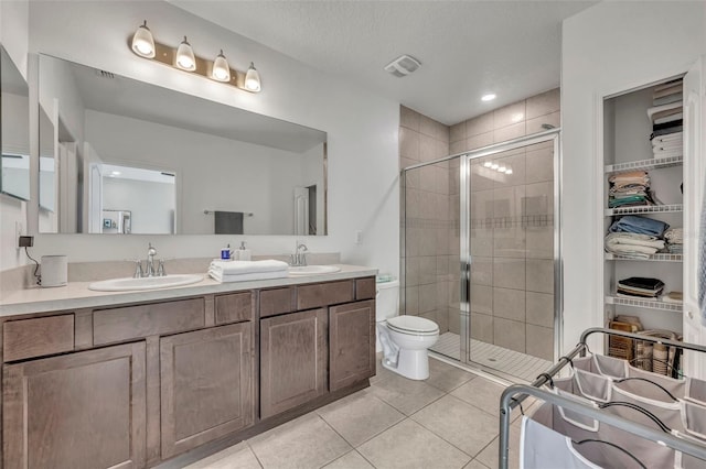 bathroom featuring tile patterned flooring, vanity, a shower with shower door, and a textured ceiling