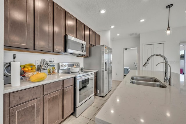 kitchen with light stone counters, sink, dark brown cabinetry, and stainless steel appliances