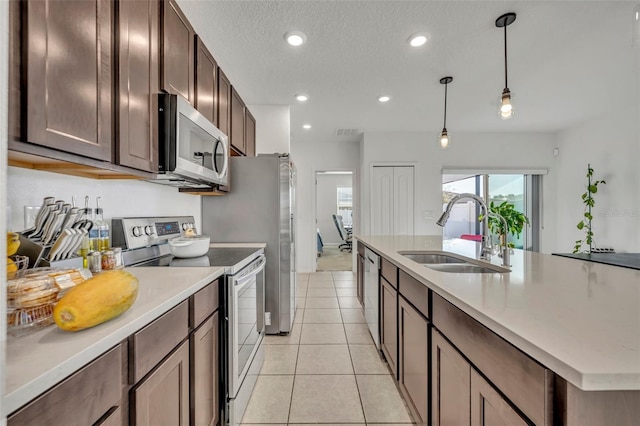 kitchen with sink, stainless steel appliances, pendant lighting, a textured ceiling, and light tile patterned floors