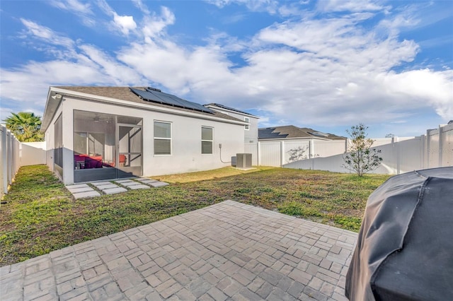 back of property featuring solar panels, central AC, a patio area, a sunroom, and a yard