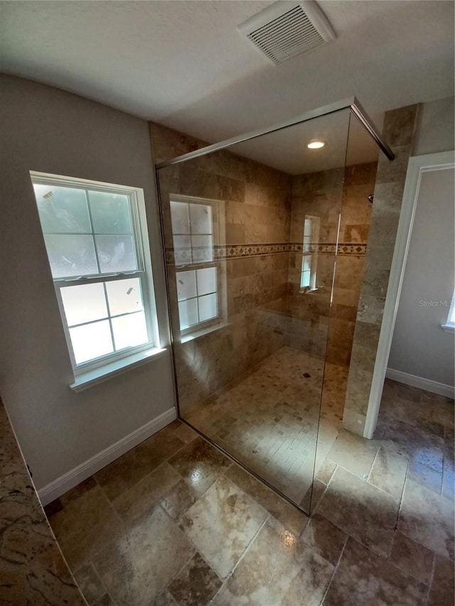 bathroom featuring visible vents, a walk in shower, and baseboards