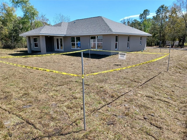 rear view of house with stucco siding, french doors, and a shingled roof