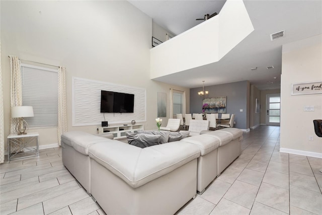 tiled living room featuring a towering ceiling and an inviting chandelier