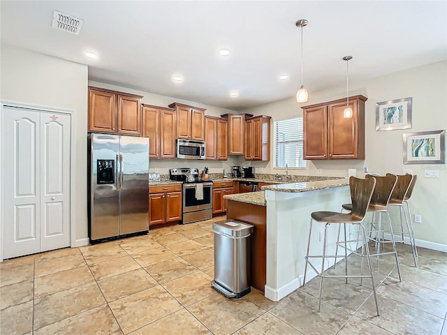 kitchen with pendant lighting, a kitchen bar, light stone counters, kitchen peninsula, and stainless steel appliances