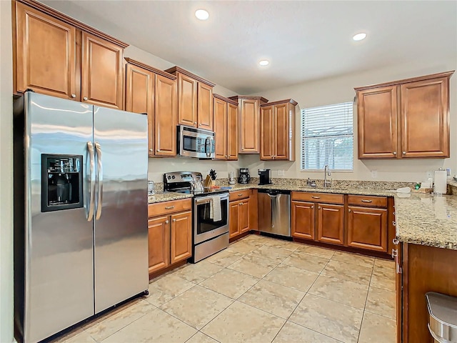 kitchen with light stone countertops, stainless steel appliances, light tile patterned flooring, and sink