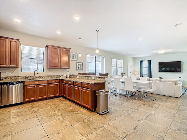 kitchen featuring pendant lighting, dishwasher, light stone counters, and a wealth of natural light