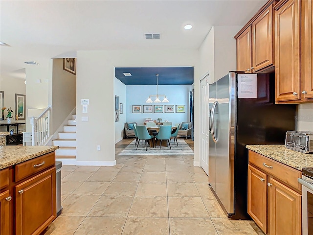 kitchen with stainless steel fridge with ice dispenser, light stone counters, light tile patterned floors, and hanging light fixtures