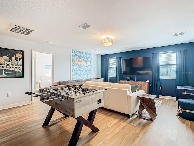 rec room with light hardwood / wood-style floors and a textured ceiling