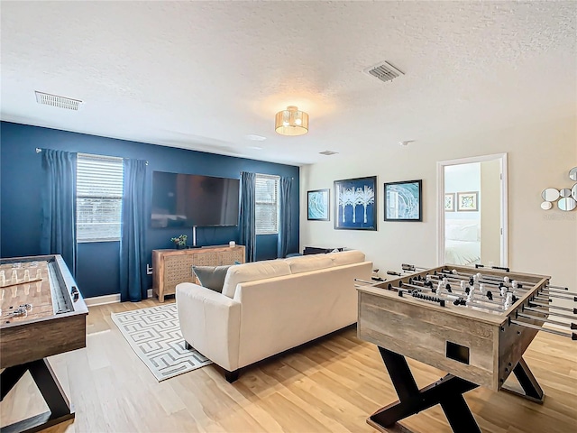 game room featuring plenty of natural light, a textured ceiling, and light hardwood / wood-style flooring