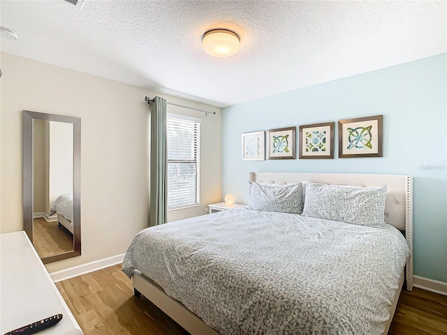 bedroom with a textured ceiling and hardwood / wood-style flooring