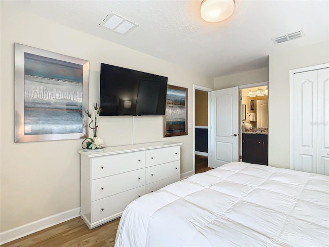 bedroom with ensuite bath, a closet, and wood-type flooring