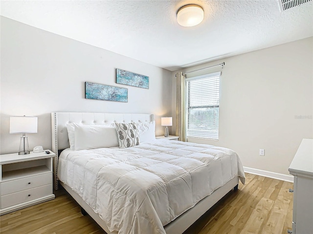 bedroom with light hardwood / wood-style flooring and a textured ceiling