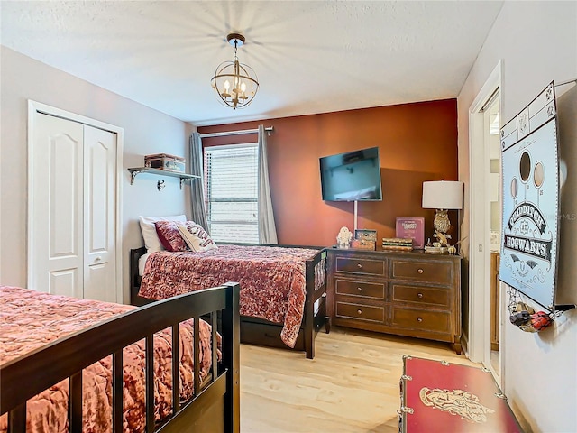 bedroom with light wood-type flooring, a closet, and a notable chandelier