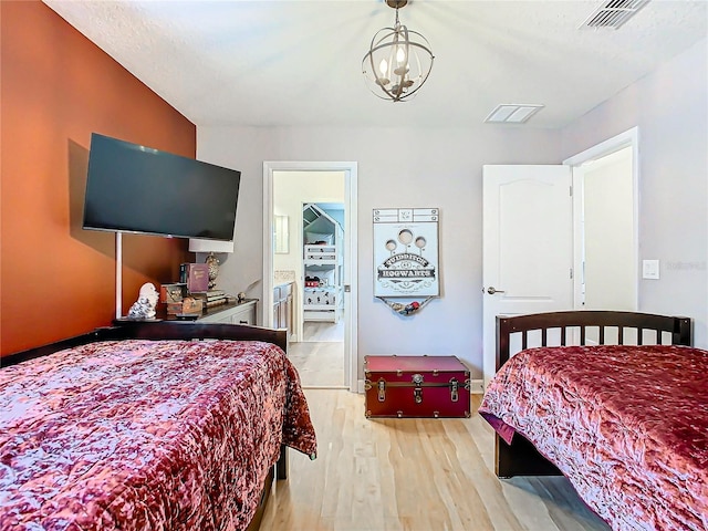 bedroom with an inviting chandelier and light hardwood / wood-style flooring