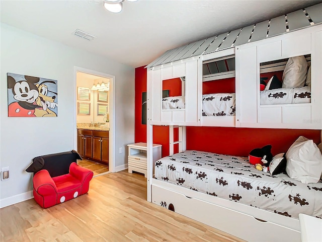 bedroom with light wood-type flooring and connected bathroom