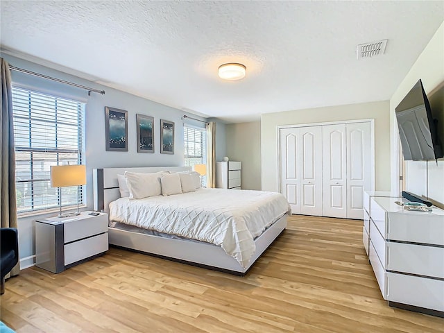 bedroom with a textured ceiling, light hardwood / wood-style flooring, and a closet