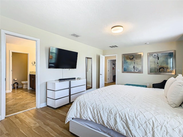 bedroom with ensuite bath and light hardwood / wood-style flooring