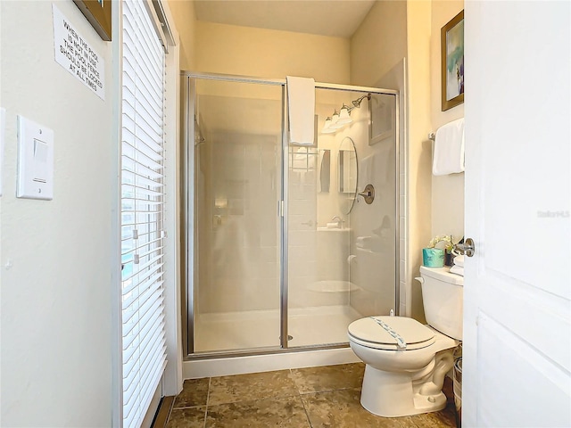 bathroom featuring a shower with door and toilet