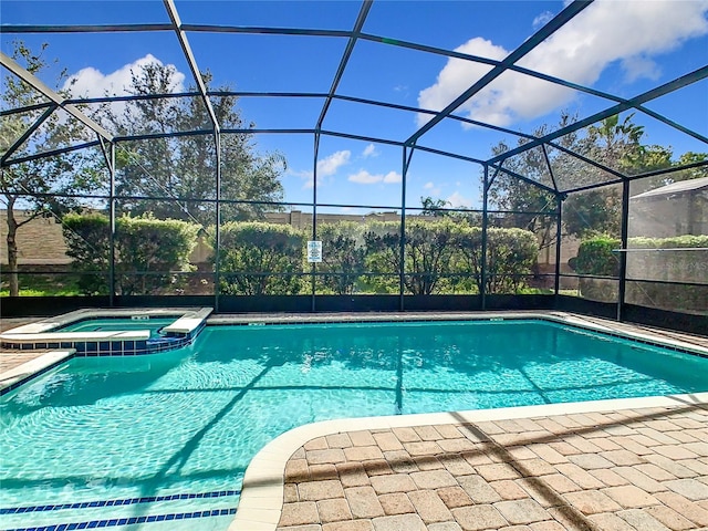 view of swimming pool featuring glass enclosure and an in ground hot tub