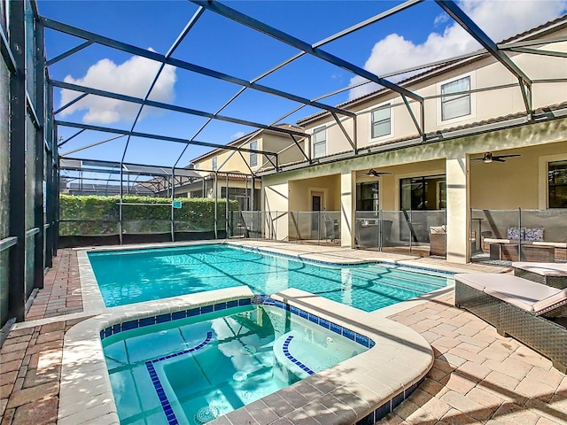 view of pool with glass enclosure, an in ground hot tub, ceiling fan, and a patio