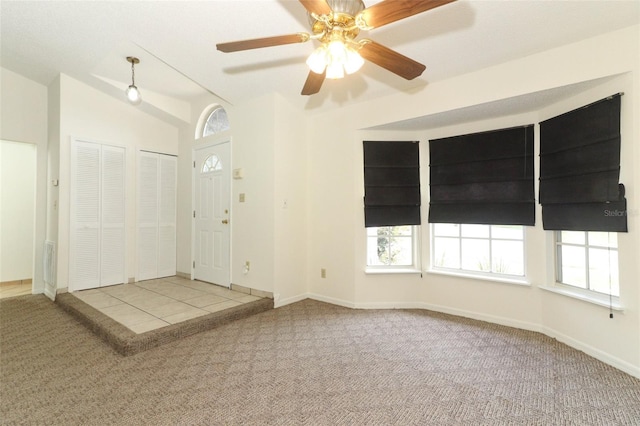 carpeted entryway with ceiling fan and lofted ceiling