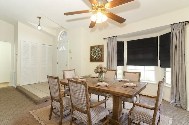 carpeted dining room with ceiling fan and vaulted ceiling