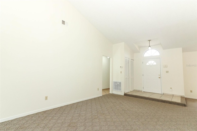 foyer entrance featuring high vaulted ceiling and light colored carpet