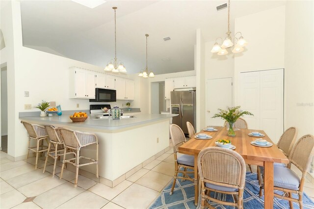 kitchen with light tile patterned flooring, kitchen peninsula, stainless steel refrigerator with ice dispenser, white cabinets, and pendant lighting