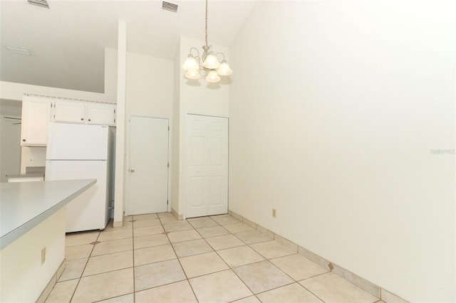 kitchen with white cabinets, hanging light fixtures, a chandelier, light tile patterned floors, and white fridge