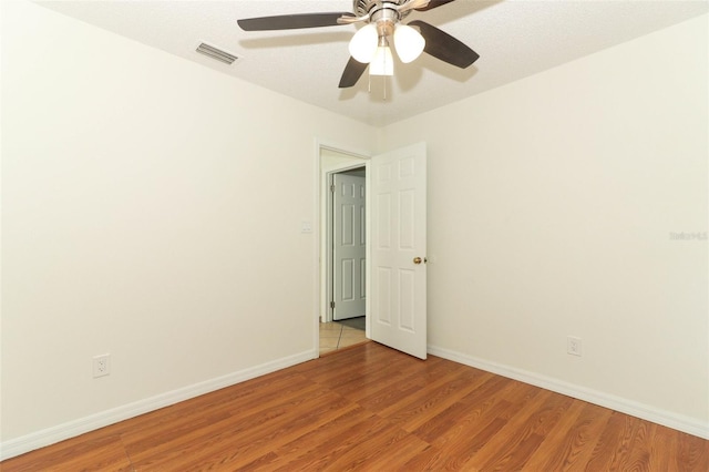 empty room featuring light wood-type flooring, a textured ceiling, and ceiling fan