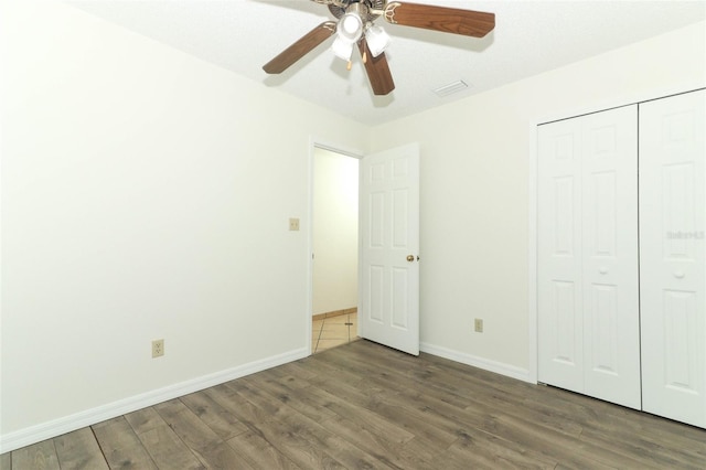 unfurnished bedroom featuring dark wood-type flooring, a closet, a textured ceiling, and ceiling fan