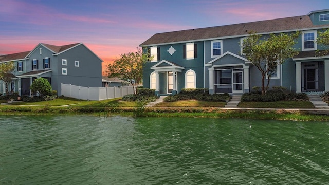 view of front of property featuring a water view and a lawn