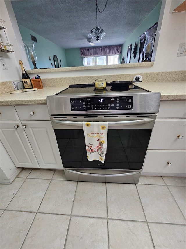 721 S Beach St Unit 217A, Daytona Beach, FL 32114 - kitchen with pendant lighting, a textured ceiling, light tile patterned floors, stainless steel stove, and white cabinetry