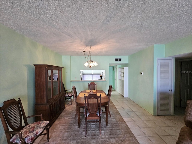 721 S Beach St Unit 217A, Daytona Beach, FL 32114 - dining area featuring a textured ceiling, light tile patterned floors, and an inviting chandelier
