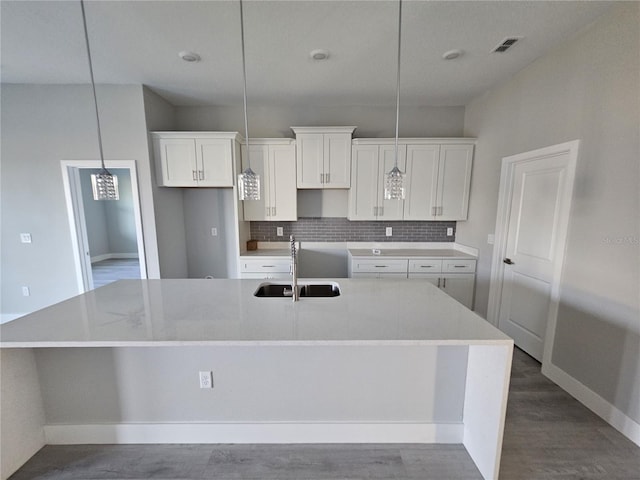 kitchen featuring white cabinetry, sink, an island with sink, and pendant lighting