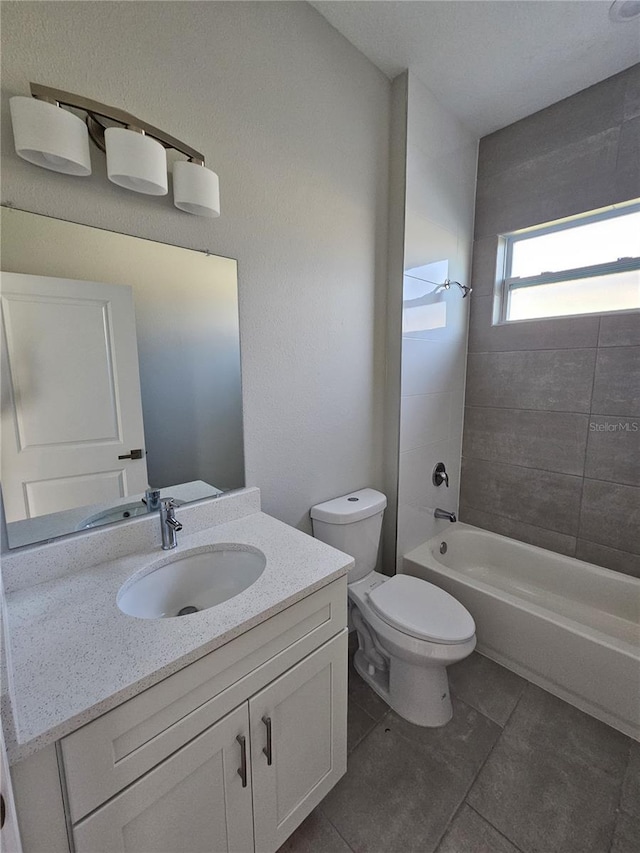 full bathroom with tile patterned floors, vanity, tiled shower / bath combo, and toilet