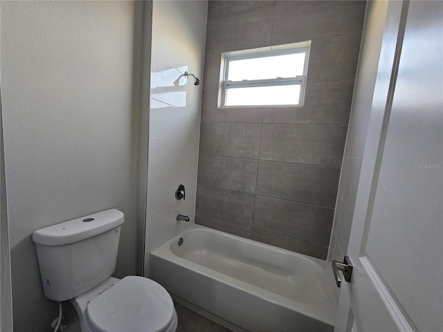 bathroom with tiled shower / bath combo and toilet