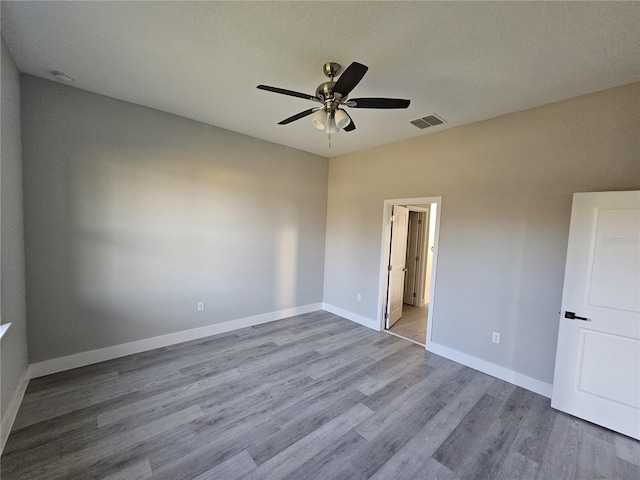 spare room with ceiling fan, light wood-type flooring, and a textured ceiling