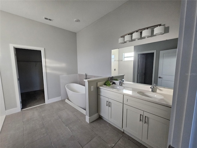 bathroom with a bathing tub, vanity, a textured ceiling, and tile patterned flooring