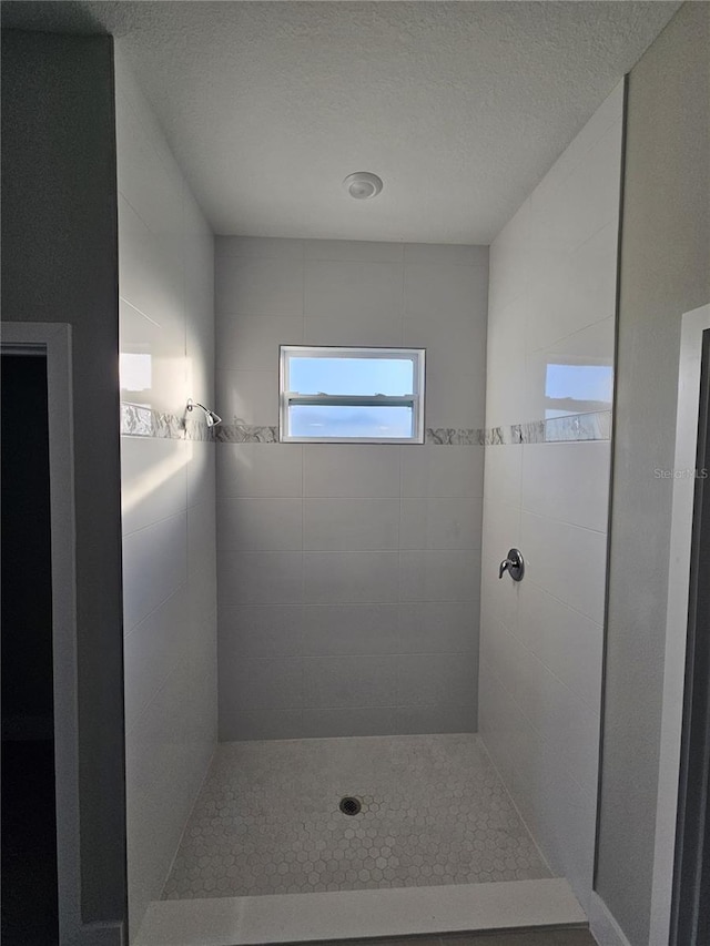 bathroom with tiled shower and a textured ceiling