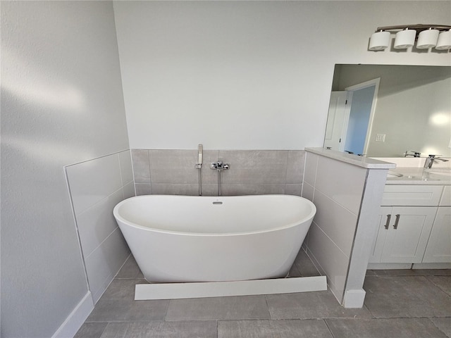 bathroom featuring tile patterned flooring, vanity, a bath, and tile walls