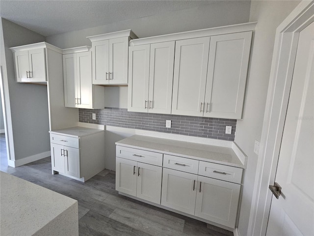 kitchen with white cabinets, decorative backsplash, a textured ceiling, and dark hardwood / wood-style floors