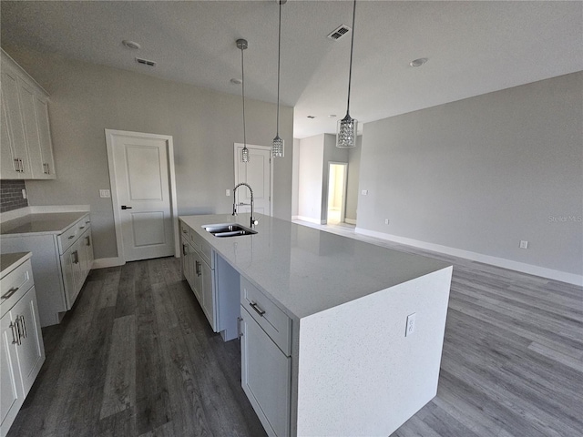 kitchen with dark hardwood / wood-style flooring, sink, pendant lighting, a center island with sink, and white cabinetry